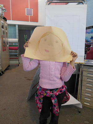 A photo of a student holding up a drawing of a face.