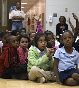 A photo of students sitting on the floor during an event.