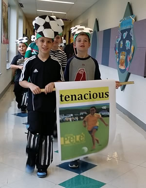 A photo of students walking down a hallway while holding a sign.